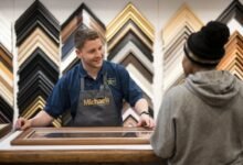 A Michaels employee assisting a customer with custom framing options, showcasing various frame styles.